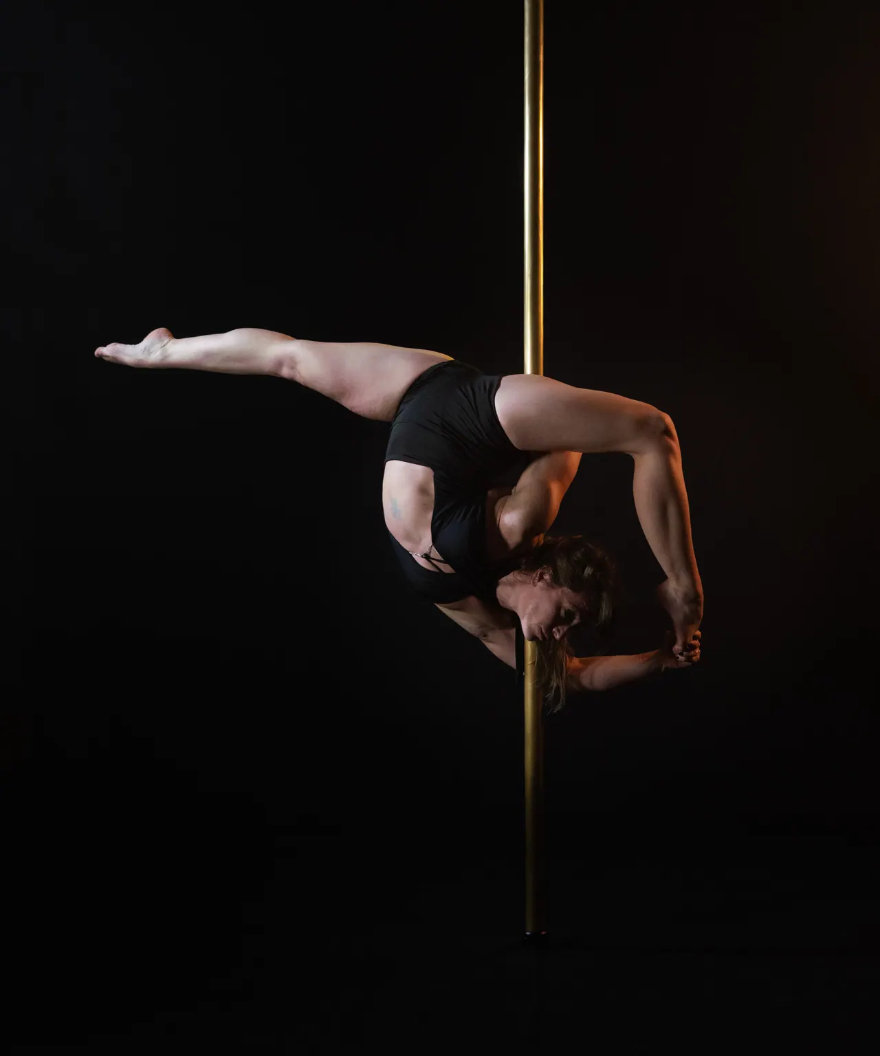 Dansatoare într-o figură de flexibilitate la bară, cu piciorul întins